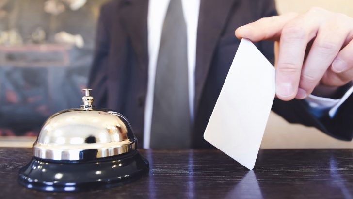 Reception service bell and receptionist holding a room key card.